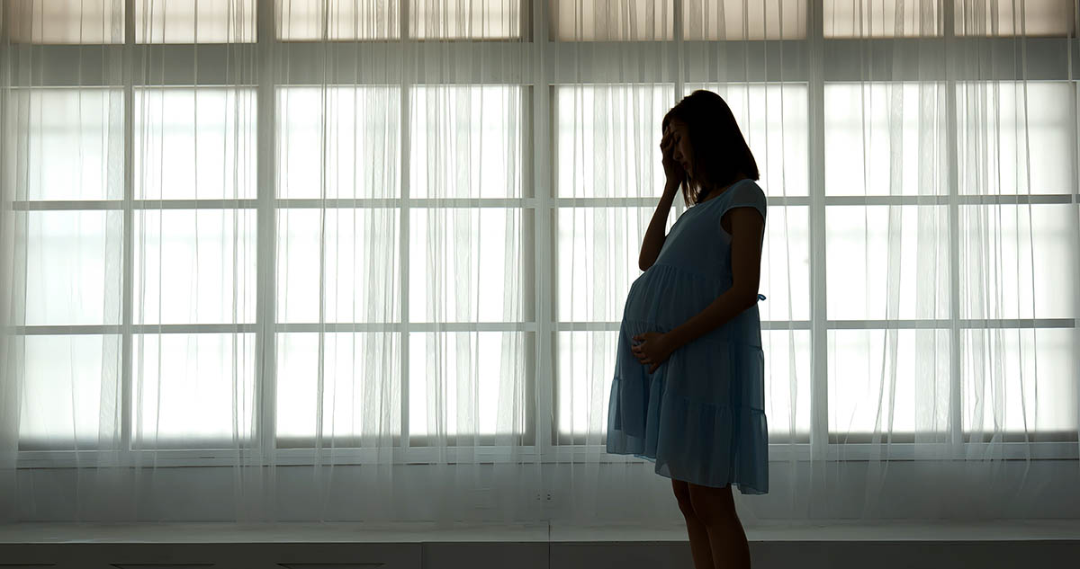 Pregnant woman standing in front of windows