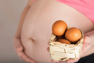 Pregnant woman holding small basket of eggs