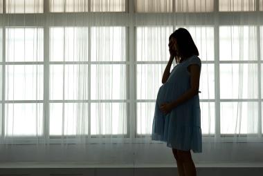 Pregnant woman standing in front of windows